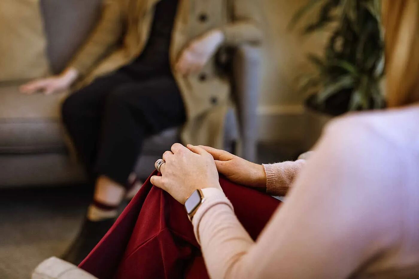 Two people sitting together in conversation in a softly lit room, seen from behind so neither is identifiable.